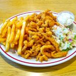 A photo of fried clams, french fries, cole slaw & tartar sauce