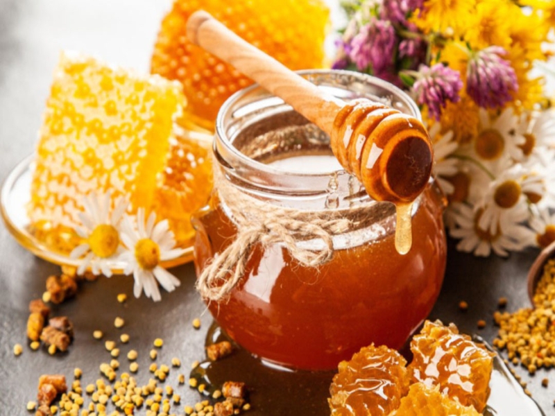 A photo of honey, honeycombs & flowers