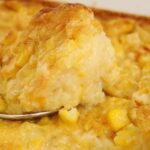 A photo of corn pudding with a spoon