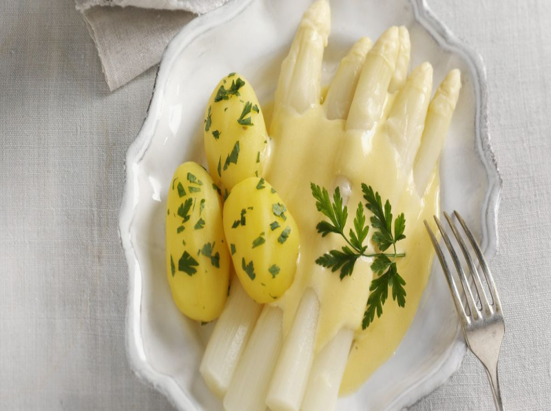 Photo of a plate of white asparagus and potatoes with hollandaise sauce