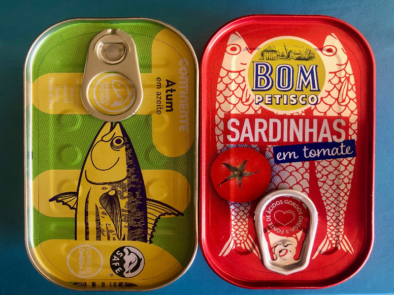 A photo of two containers of tinned fish, one green and one red can.