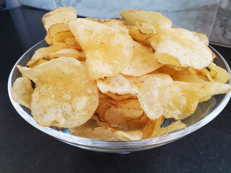 Photo of a glass bowl filled with kettle cooked potato chips