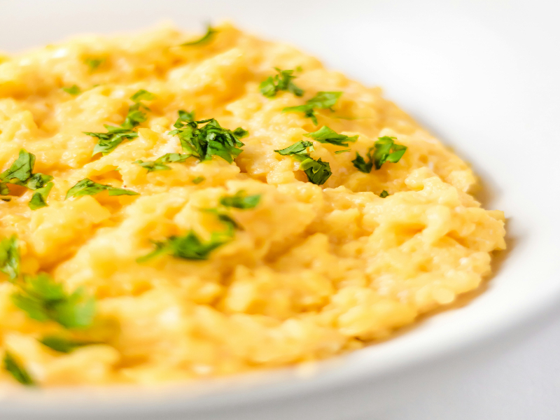 Photo of a dish of scrambled eggs with parsley sprinkled on the top.